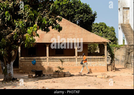 ROAD TO BISSAU, GUINEA B. - MAY 1, 2017: Unidentified local man walks with a bag in a village in Guinea Bissau. Still many people in the country live  Stock Photo