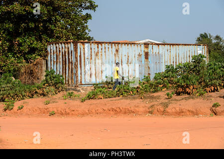 ROAD TO BISSAU, GUINEA B. - MAY 1, 2017: Unidentified local man walks near the fence in a village in Guinea Bissau. Still many people in the country l Stock Photo