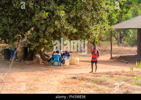 ROAD TO BISSAU, GUINEA B. - MAY 1, 2017: Unidentified local  man with backpack stands in a village in Guinea Bissau. Still many people in the country  Stock Photo