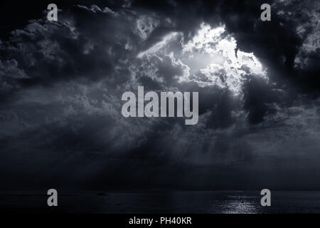 Dramatic cloudy sunset with sunbeams. Portuguese coast. Toned blue. Stock Photo