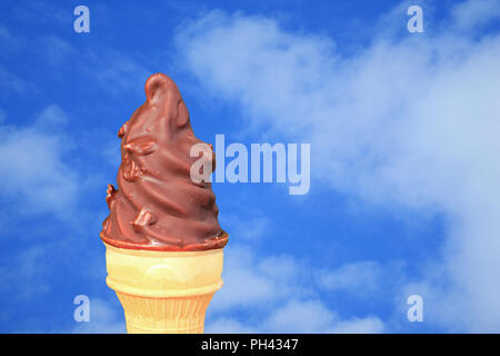 Chocolate Dipped Soft Serve Ice Cream Cone Against Vivid Blue Sky with White Cloud Stock Photo