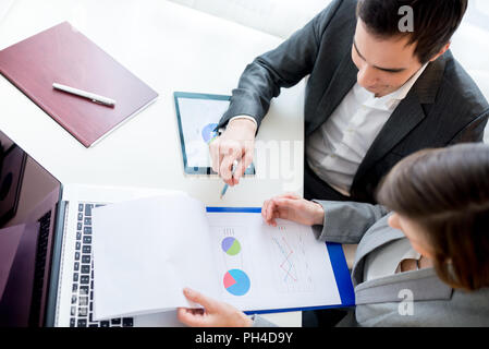 Aerial Shot of Two Business People Reviewing Charts from Business Documents While Sitting at the Worktable. Stock Photo