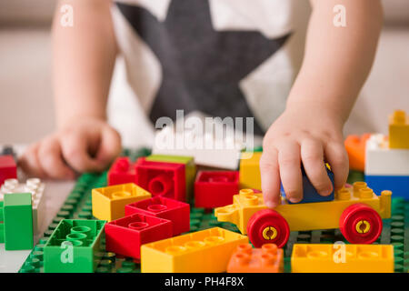 Close up of child's hands playing with colorful plastic bricks at the table. Toddler having fun and building out of bright constructor bricks. Early l Stock Photo