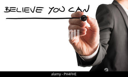Man writing the idiom Believe you can on a virtual interface with a black marker pen over white with copyspace in a motivational message. Stock Photo