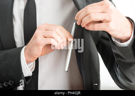 Businessman removing a pen from the pocket of his suit jacket, close up view of his hands and the pen. Stock Photo