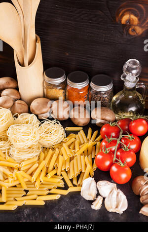 Italian cuisine from raw uncooked pasta next to fresh vegetables, different types of spices and sunflower oil Stock Photo
