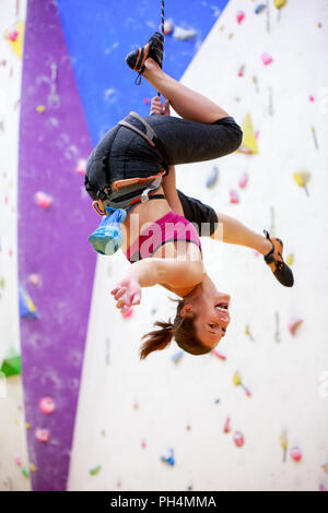 Photo of young athlete hanging upside down on wall for rock climbing Stock Photo