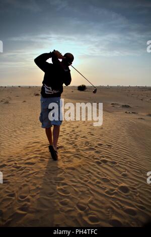 Playing golf in the desert during sunset in Dubai, United Arab Emirates Stock Photo