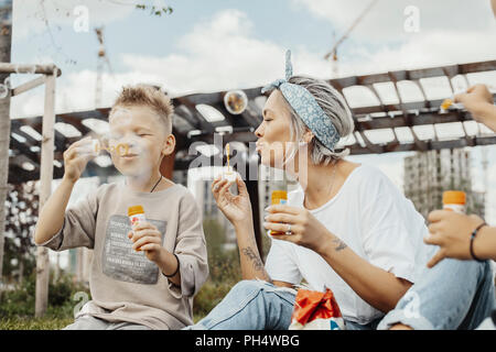 Close up of family blowing bubbles outdoors in the park. Stock Photo