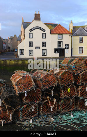 Lobsterpots on the quayside of Eyemouth Harbour, Scotland, UK. The Contended Sole restaurant behind Stock Photo