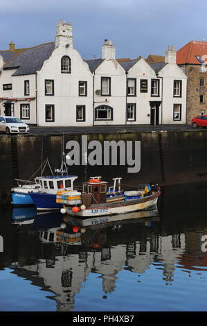 Fishing boats in Eyemouth Harbour, Scotland, UK, The Hip Inn behind and reflected in the water Stock Photo