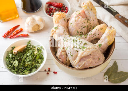 Raw chicken drumstick in marinade with sauce, pepper and herbs. Selective focus Stock Photo