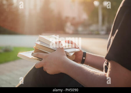 Holding a pile of student books outside of college. First year student waiting for the beginning of courses Stock Photo