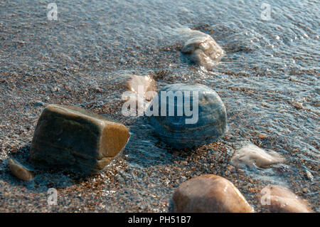 A group of pebbles by the sea shore partly immersed in sea water