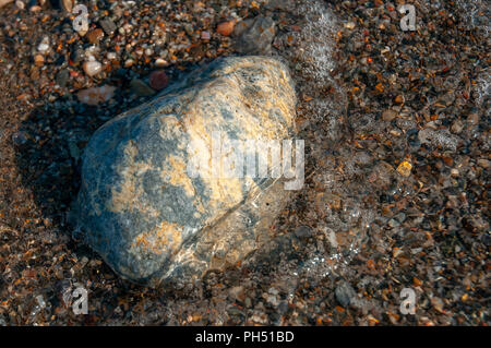 A group of pebbles by the sea shore partly immersed in sea water