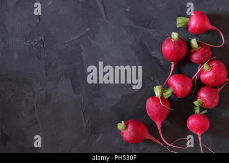 Red radishes on dark surface, flat lay, space for copy Stock Photo