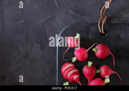 Red radishes on dark surface, flat lay, space for copy Stock Photo
