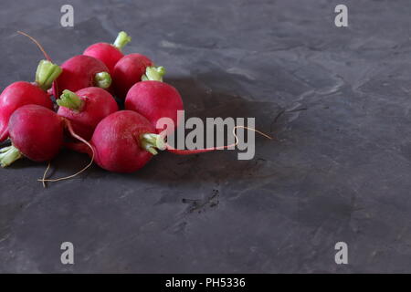 Red radishes on dark grey surface, with space for copy Stock Photo