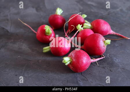Red radishes on dark grey surface, with space for copy Stock Photo