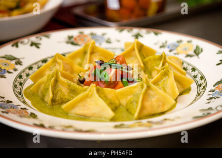 Plate of fresh ravioli in a pesto sauce.. Stock Photo