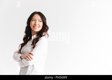 Portrait of young asian woman with long dark hair looking aside at copyspace with arms crossed isolated over white background in studio Stock Photo