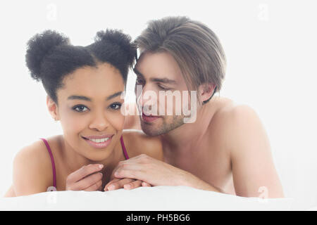 portrait of young interracial couple resting in bed together in morning at home Stock Photo