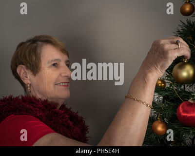 Horizontal portrait of an elderly woman decorating a Christmas tree Stock Photo
