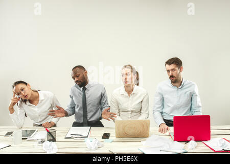 Young upset african and caucasian men and women sitting at office and working on laptops. The business, emotions, team, teamwork, workplace, leadership, meeting concept. different emotions of colleagues Stock Photo