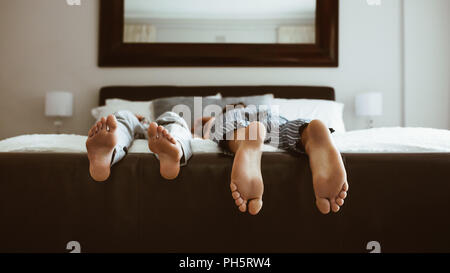 Feet of two people sleeping on bed. People sleeping on bed in different positions. Stock Photo
