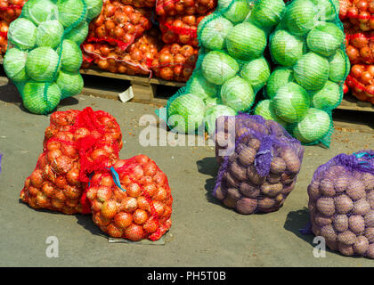 Fresh young vegetables in bags on the counter, cabbage, onions, potatoes, Stock Photo