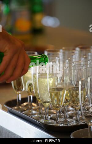 hand holding a bottle of sparkling wine, pouring in champagne cups Stock Photo