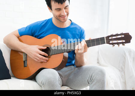 Asian young man hands playing acoustic guitar at home. Enjoy playing acoustic guitar for relax in holiday. Stock Photo
