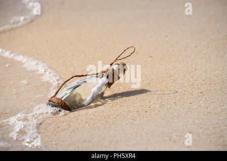 Letter message in a glass transparent bottle on the beach , concept for communication. Stock Photo