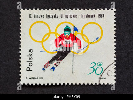 A used postage stamp, in dark background, from Poland to commemorate 1964 Winter Olympic in Innsbruck, Austria. Stock Photo