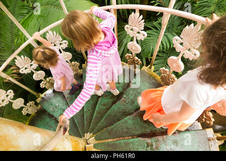 Kids / children descend iron spiral staircase in the restored / after the 2018 restoration / Victorian Temperate House at the Royal Botanic Garden, Kew. London UK Stock Photo