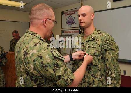 NAVAL BASE KITSAP - BANGOR (July 26, 2018) Master-at-Arms 1st Class Shawn D. Shirley receives the Navy and Marine Corps Achievement Medal by Capt. Alan Schrader, commanding officer of Naval Base KItsap (NBK), for work done during the Final Evaluation Problem (FEB). FEB is an evaluation of an installation's security and emergency management response to a force protection situation. NBK is the first major installation to pass the evaluation. Stock Photo