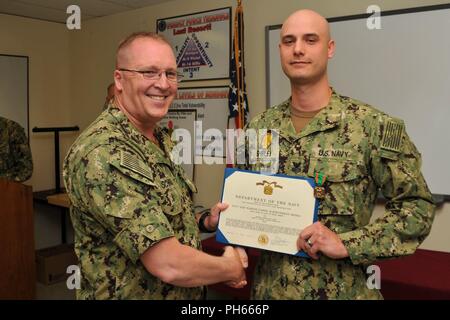 NAVAL BASE KITSAP - BANGOR (July 26, 2018) Master-at-Arms 1st Class Shawn D. Shirley receives the Navy and Marine Corps Achievement Medal by Capt. Alan Schrader, commanding officer of Naval Base KItsap (NBK), for work done during the Final Evaluation Problem (FEB). FEB is an evaluation of an installation's security and emergency management response to a force protection situation. NBK is the first major installation to pass the evaluation. Stock Photo