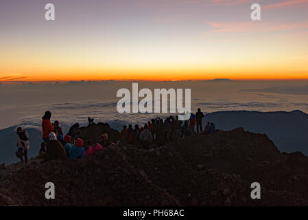 People on the summit of volcano Rinjani watching sunrise, Lombok, Indonesia Stock Photo