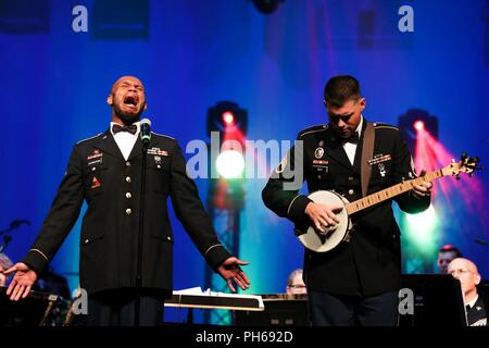 U.S. Army Spc. Joseph Leveston vocalist and Staff Sgt. James Old on the banjo soldiers with the 389th U.S. Army Materiel Command Band perform banjo music of the Tennessee Valley at Bob Jones High School, Alabama, June 26, 2018. The AMC Band performed to a packed audience during their final concert before inactivation. Stock Photo