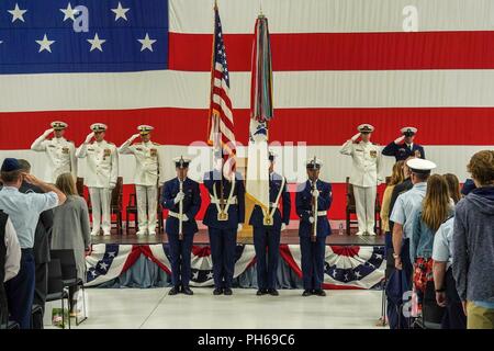 A Coast Guard Air Station Sitka color guard presents the colors during the National Anthem at Air Station Sitka, Alaska, June 28, 2018. Air Station Sitka held a change of command where Capt. William Lewin transferred command to Cmdr. Michael Frawley. Stock Photo