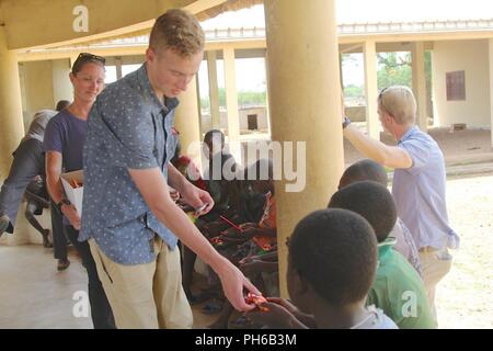 Pvt. Joseph Treece of the Task Force Darby, 1st Battalion, 32nd Infantry Regiment, 10th Mountain Division security force, hands out candy donated by U.S. citizens to the children of Saare Jabbaama, a children’s home near Contingency Location, Garoua in Cameroon June 28, 2018. TF Darby service members are serving in a support role for the Cameroonian Military’s fight against the violent extremist organization Boko Haram. Stock Photo