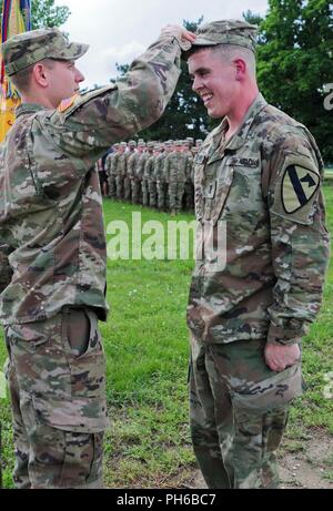 Capt. Trevor Sparkes, commander of the Headquarters and Headquarters Company, 2nd Battalion, 5th Cavalry Regiment, 1st Armored Brigade Combat Team, 1st Cavalry Division, pins 2nd Lt. Steven Schworm, assigned to 2-5 Cav, 1st ABCT, 1st CD, with the rank of first lieutenant at Mihail Kogalniceanu Air Base in Romania, June 29, 2018. Schworm originates from Spencerport, New York and is deployed with the 2-5 Cav in support of Atlantic Resolve, an enduring training exercise between NATO and U.S. Forces. Stock Photo