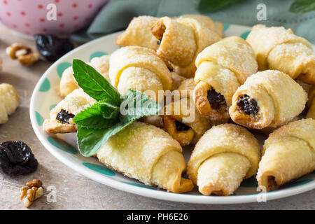 Homemade cookies with dried prunes and walnuts on a plate on a table, bagels close-up. Stock Photo