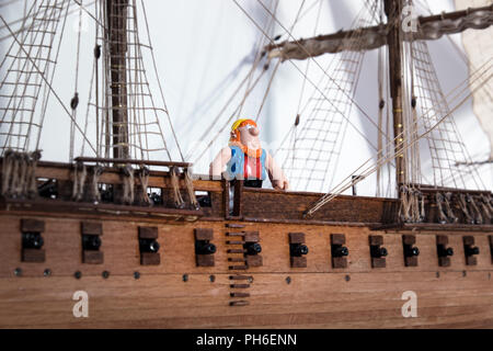 Pirate figure standing on a model of an old scale model ship. Stock Photo