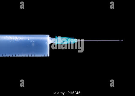 Blue illuminated syringe with sharp needle close up. Isolated on black, clipping path included Stock Photo