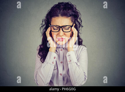 Woman in glasses holding fingers on temples trying to concentrate on decision making looking stressed Stock Photo