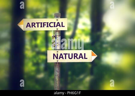 Arrows on pole showing opposite direction to artificial against natural on green woods background Stock Photo