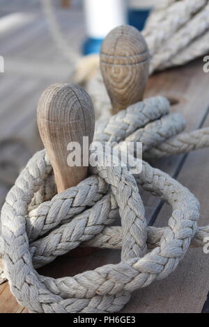 Belaying pins with braided ropes on the main deck of a clipper ship Stock Photo