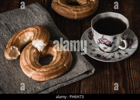 Round eclairs with cup of coffee. Sweet breakfast. Stock Photo