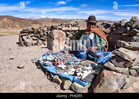 An Andean lady sells items to tourists on a remote road in the Uyuni region of Bolivia Stock Photo